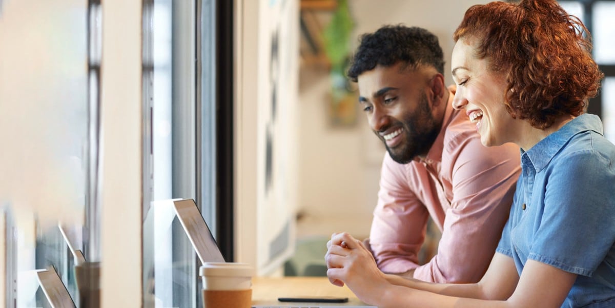 two professionals at a desk looking at a laptop