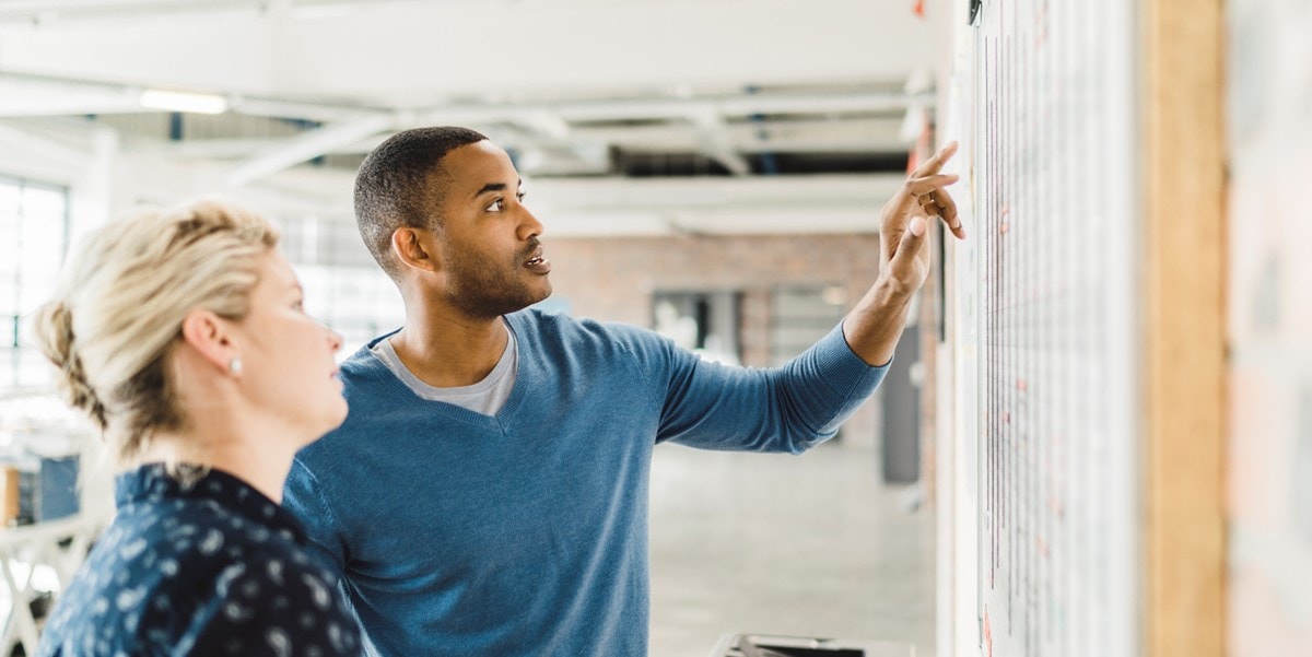 two professionals in the office looking at board