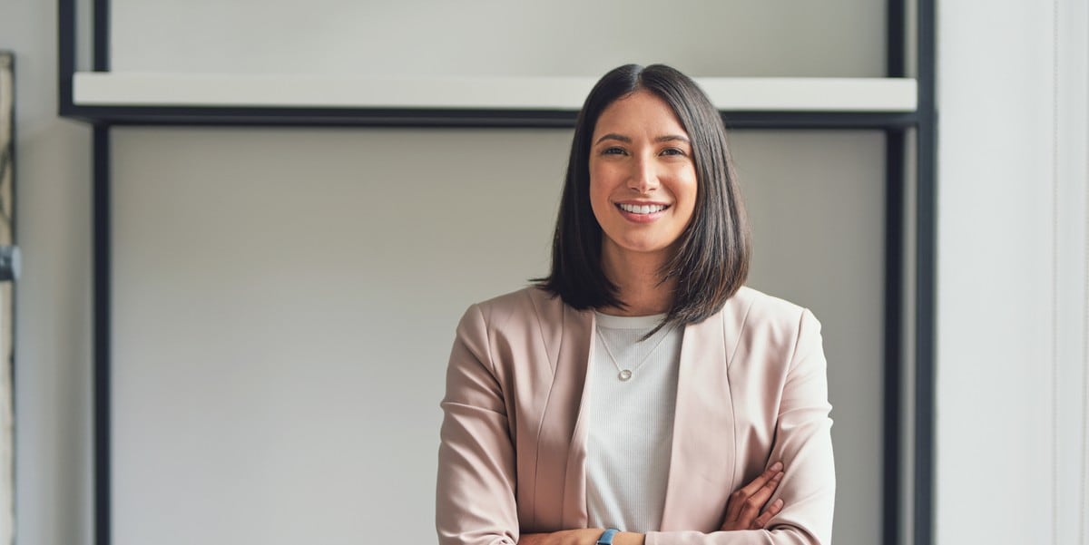 professional woman smiling with arms crossed, in the office