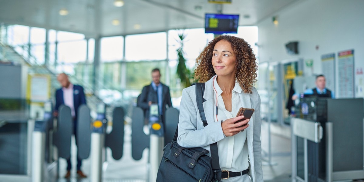 woman with a bag and coffee cup in hand, in a building lobby
