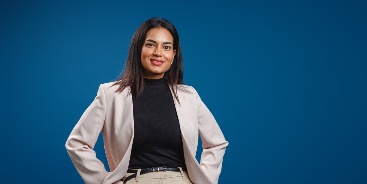 professional woman smiling, standing in front of blue background