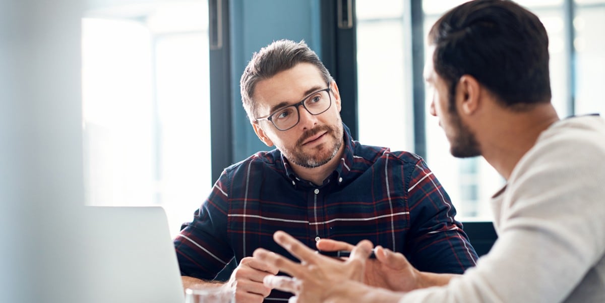 two professionls meeting in the office, seated at a desk