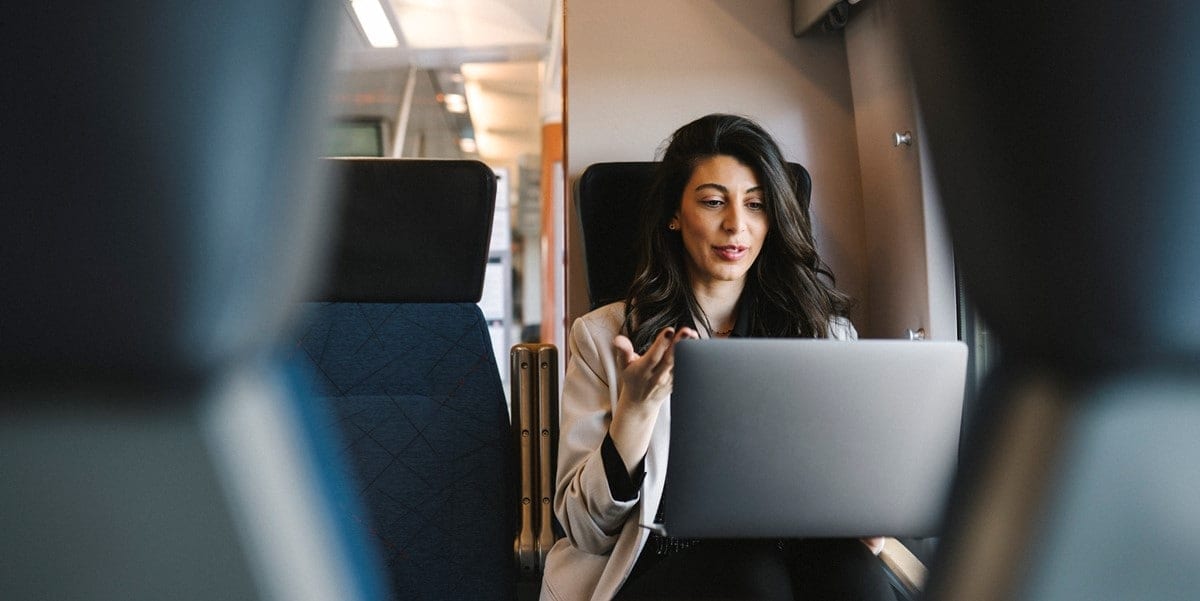 professional woman, traveler, sitting on a train, working on laptop