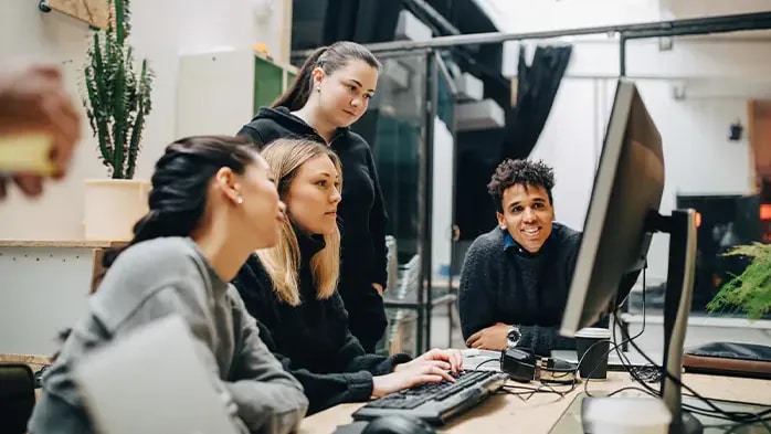group on four people discussing work on a laptop